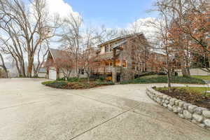 View of side of property with a balcony, concrete driveway, a garage, and stucco siding