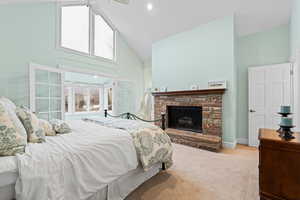 Bedroom featuring high vaulted ceiling, light carpet, and a fireplace with raised hearth