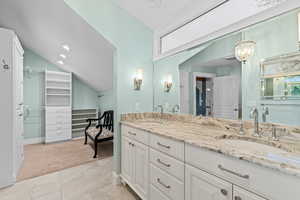 Full bathroom with a spacious closet, double vanity, lofted ceiling, recessed lighting, and light carpet