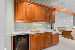 Kitchen with brown cabinets, light carpet, dishwasher, tile counters, and recessed lighting