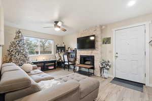 Living room featuring a fireplace, light wood finished floors, and ceiling fan