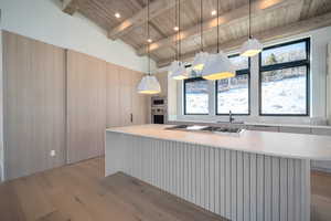 Kitchen with decorative light fixtures, light wood-style floors, appliances with stainless steel finishes, wood ceiling, and a center island