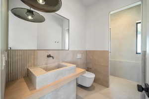 Full bathroom with a wainscoted wall, vanity, and tile walls