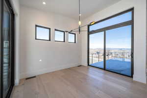 Empty room featuring a mountain view, plenty of natural light, light wood finished floors, a chandelier, and recessed lighting