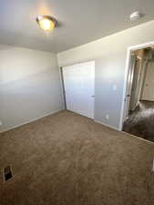 Unfurnished bedroom featuring a closet and dark colored carpet