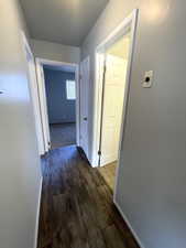 Hall featuring dark wood-type flooring and baseboards