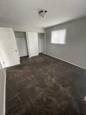 Unfurnished bedroom with multiple closets and dark colored carpet