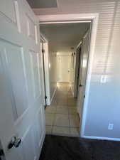 Hall with light tile patterned floors and light carpet