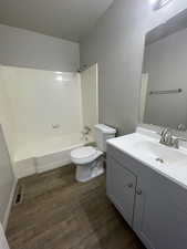 Bathroom with vanity, dark wood finished floors, and shower / bathtub combination