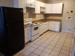 Kitchen featuring white appliances, white cabinets, and light tile patterned floors