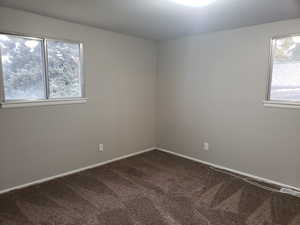 Unfurnished room with baseboards and dark carpet