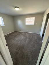 Unfurnished bedroom featuring dark carpet and a closet