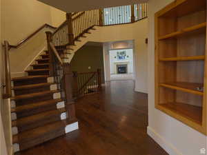 Staircase with built in shelves, a fireplace, hardwood / wood-style floors, and a high ceiling