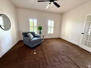 Living area featuring dark colored carpet and ceiling fan