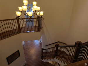 Stairs with a chandelier and wood finished floors