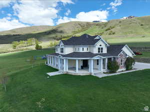 View of front of property featuring roof with shingles, covered porch, a front lawn, a mountain view, and driveway