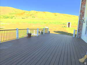 Wooden terrace featuring a mountain view and a lawn