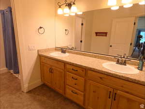 Bathroom with double vanity, a shower with curtain, and dark tile patterned floors