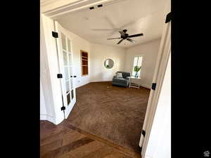 Living area featuring dark carpet and a ceiling fan