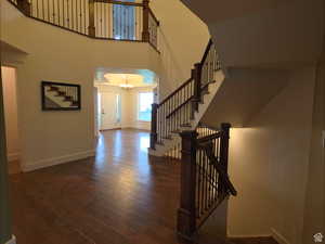 Entrance foyer with stairs, a towering ceiling, dark wood-style floors, and a chandelier