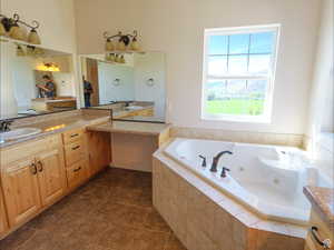 Bathroom featuring vanity, a whirlpool tub, and dark tile patterned flooring