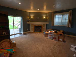 Carpeted living area with a textured ceiling, a glass covered fireplace, healthy amount of natural light, and recessed lighting