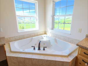 Bathroom featuring vanity, a jetted tub, and healthy amount of natural light
