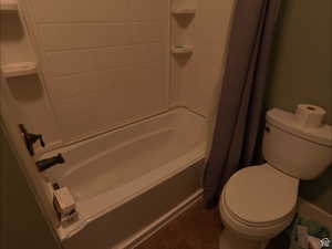 Full bathroom featuring dark tile patterned floors and shower / bath combo