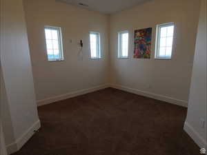 Empty room featuring dark carpet and baseboards