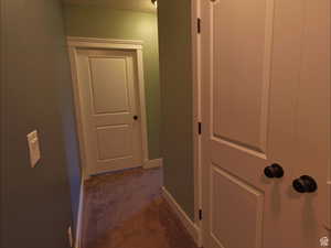 Corridor with dark carpet and baseboards