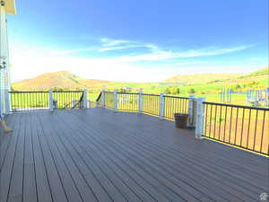 Wooden terrace featuring a mountain view and a lawn