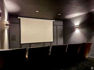 Home theater room with a textured wall, a textured ceiling, carpet flooring, and recessed lighting