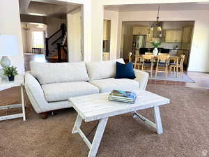 Carpeted living area with a chandelier and stairway