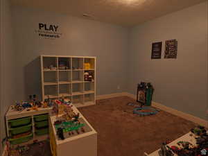 Rec room featuring carpet and a textured ceiling