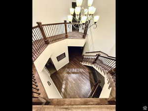Stairs with a chandelier and wood-type flooring