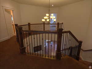 Stairway with carpet flooring and a chandelier