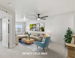 Living area featuring carpet, ceiling fan, and a textured ceiling