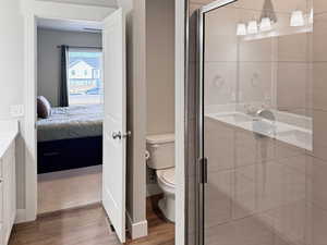 Ensuite bathroom with vanity, a stall shower, and light wood-style flooring