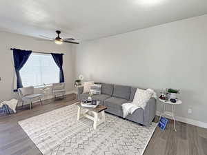 Living area featuring ceiling fan, wood finished floors, and a textured ceiling