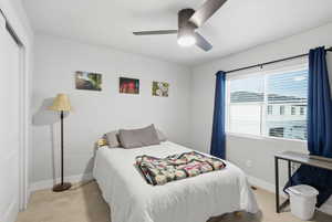 Bedroom with light carpet, ceiling fan, and a closet