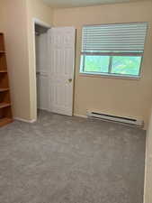 Unfurnished bedroom featuring a baseboard radiator, carpet flooring, and a closet