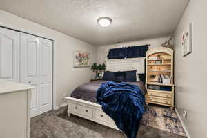 Bedroom featuring dark colored carpet, a textured ceiling, and a closet