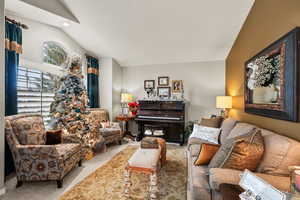 Carpeted living room featuring lofted ceiling