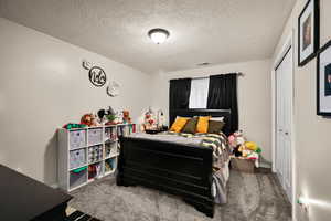 Bedroom with a textured ceiling, carpet floors, and a closet
