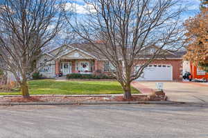 View of front of home with driveway, brick siding, and a porch