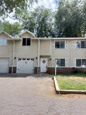 View of front of home featuring asphalt driveway, brick siding, and a front yard
