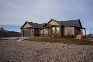 View of front of property featuring a standing seam roof, a metal roof, concrete driveway, a front yard, and a garage