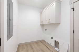 Laundry area featuring cabinet space, light wood finished floors, electric panel, electric dryer hookup, and hookup for a washing machine