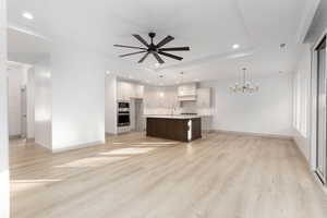 Kitchen featuring open floor plan, light countertops, a chandelier, white cabinets, and pendant lighting