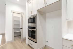 Kitchen featuring stainless steel appliances, light wood-type flooring, white cabinetry, and recessed lighting